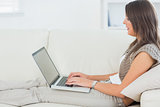Woman lying on the sofa and using her laptop