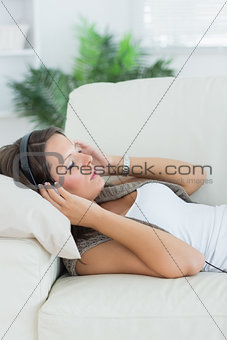 Relaxed woman lying on the sofa and listening music