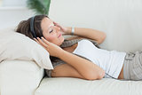 Smiling woman lying on the sofa and listening music