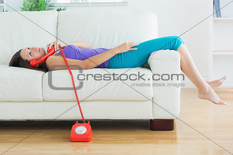 Happy woman lying on the sofa and phoning