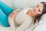 Sick woman lying on sofa with stomach ache