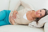 Woman lying on the sofa with upset stomach