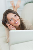 Thoughtful and smiling woman using her laptop