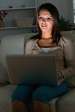 Woman sitting and watching her laptop in the dark