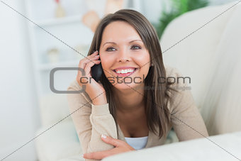 Cheerful woman lying on the sofa and calling