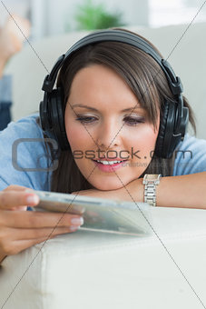 Woman listening music and looking at cd on sofa