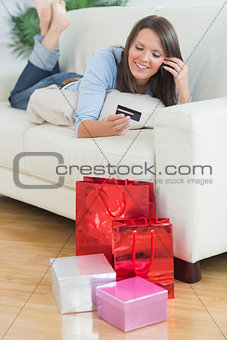 Woman looking at credit card and phoning