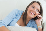 Smiling woman lying on sofa and calling
