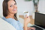 Brunette using her laptop and drinking a cup of coffee