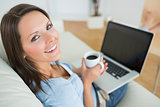 Woman drinking a coffee and using her laptop