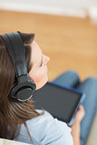 Woman listening music with her digital tablet on sofa