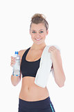 Woman standing holding a bottle and towel in sportswear