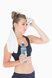 Woman standing holding a bottle of water and a white towel