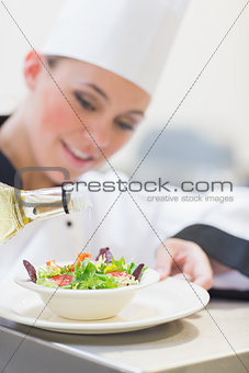Chef pouring olive oil over salad
