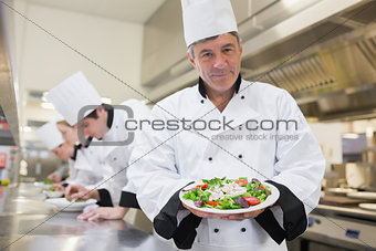 Cheerful chef presenting his salad