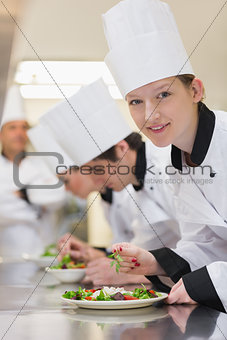 Smiling chef looking up from preparing salad
