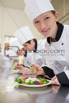Smiling chef preparing salad in culinary class