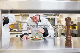 Smiling chef garnishing salad