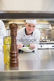 Smiling chef garnishing a salad and looking up