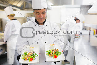 Chef admiring two salmon dishes in his hands