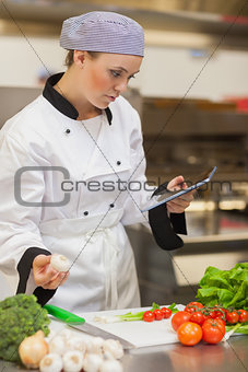 Chef consulting digital tablet before preparing vegetables
