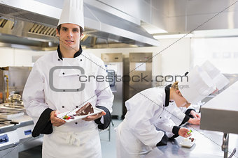 Chef's preparing deserts with one chef presenting his dish
