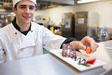 Smiling chef garnishing a slice of cake