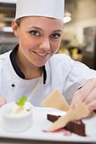 Smiling chef garnishing a slice of cake with wafers