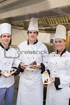 Three happy Chef's presenting cakes