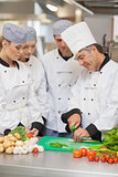 Chef teaching cutting vegetables to three trainees
