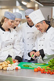Chef teaching trainees how to cut vegetables