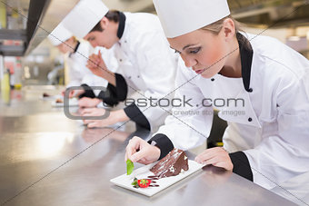 Chef's team garnishing slices of cake