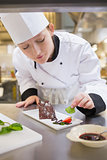 Female chef putting mint with cake