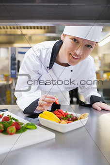Smiling chef preparing fruit salad