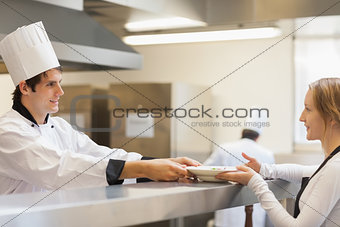 Chef giving a plate to the waitress