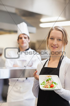 Smiling waitress presenting salmon dish