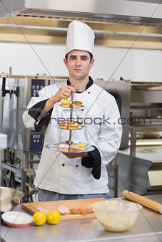 Pastry chef holding tiered cake tray