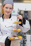 Smiling chef holding tiered cake tray