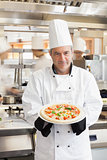 Chef showing pizza in busy kitchen