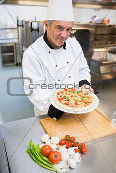 Cheerful man presenting a pizza