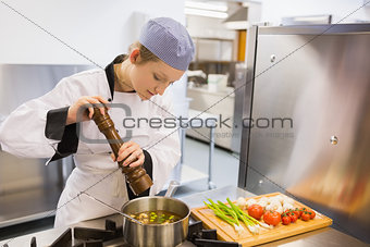 Woman spicing soup in kitchen