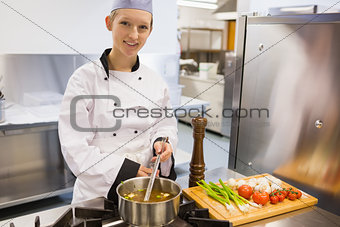 Smiling chef stirring soup