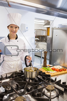 Woman cooking while using tablet pc