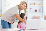 Mother pointing at laptop with daughter