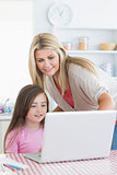 Woman and girl standing and sitting looking at laptop