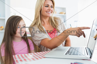 Mother pointing something out on laptop for daughter
