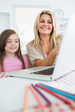 Mother and daughter smiling at laptop
