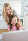 Little girl pointing at laptop and laughing with mother