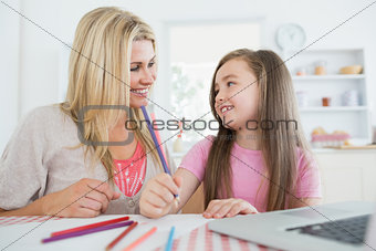 Woman and daughter smiling at each other and drawing