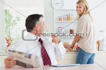 Couple standing and sitting at the kitchen smiling before work